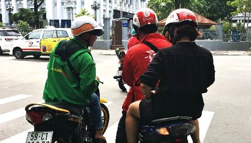 Tài xế mặc áo Mai Linh Bike đội nón Vato hỏi thăm đường tài xế Go-Viet tại TP HCM. Ảnh: Viễn Thông