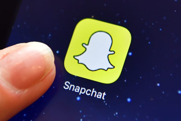 A finger is posed next to the Snapchat app logo on an iPad.