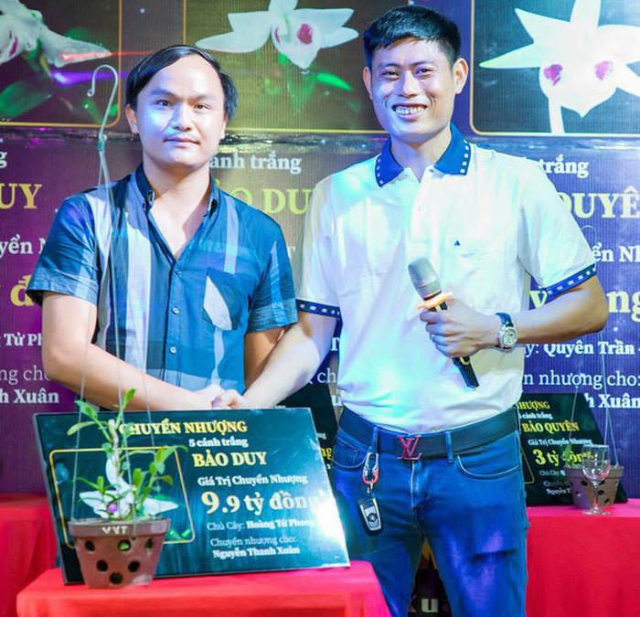 Anh Nguyễn Thanh Xuân (bên phải) cạnh chậu lan Bảo Duy 5 cánh trắng trị giá 9,9 tỷ đồng được chuyển nhượng hôm 10/6.